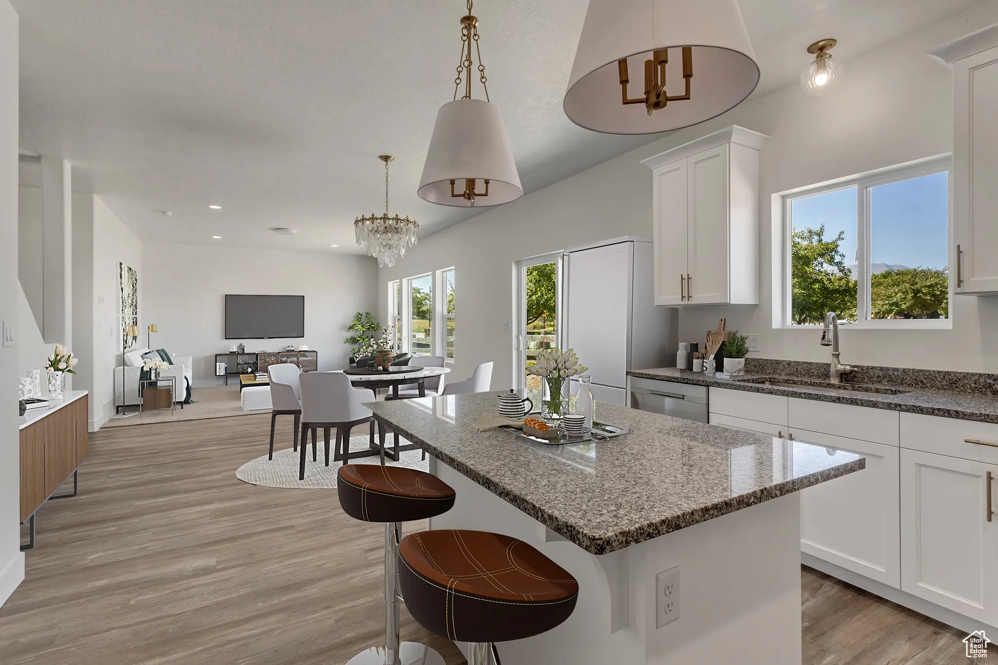 Kitchen with dark stone countertops, light wood finished floors, open floor plan, and white cabinetry