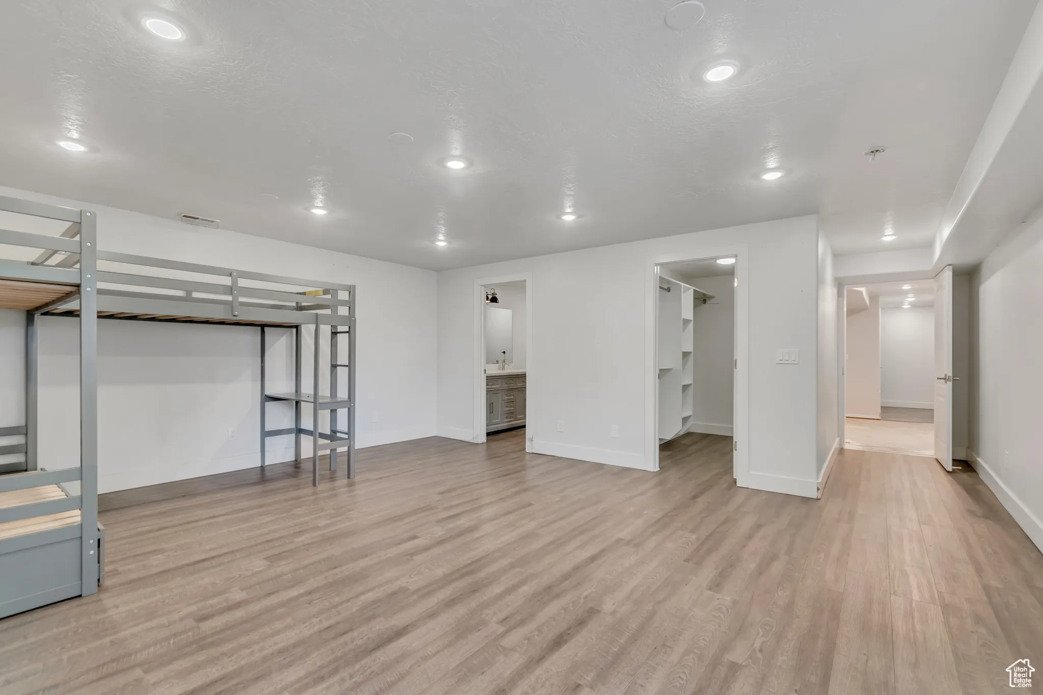 Finished basement with light wood-style flooring and recessed lighting