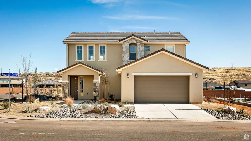 Traditional-style home featuring stucco siding, a garage, driveway, a tile roof, and stone siding