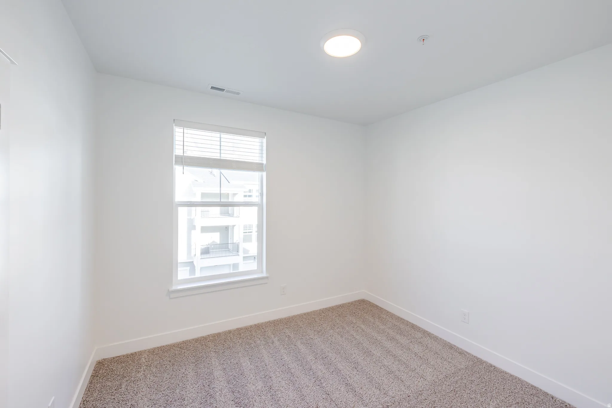 Spare room featuring light colored carpet and baseboards