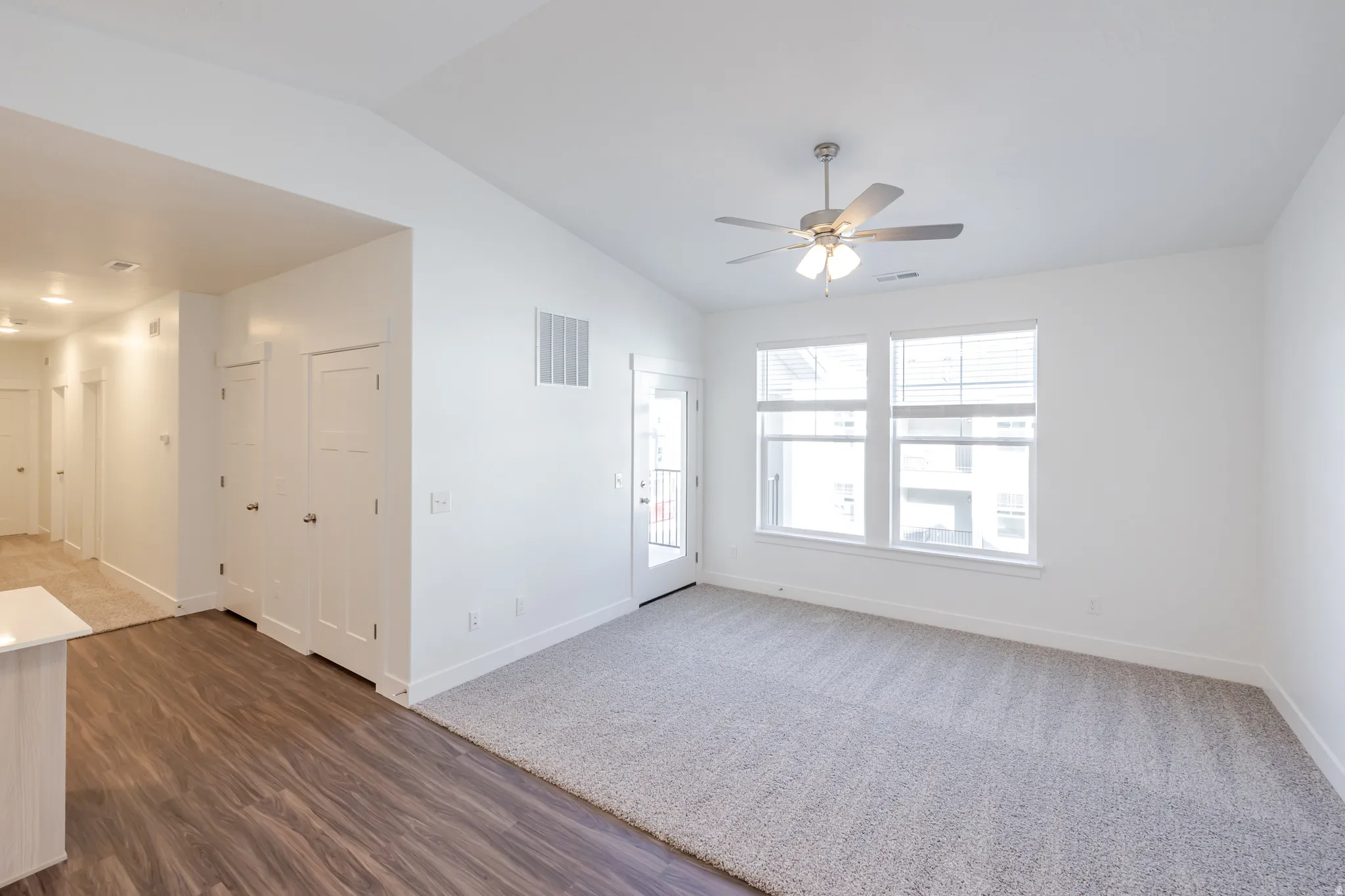 Empty room featuring vaulted ceiling, ceiling fan, and dark wood-style floors