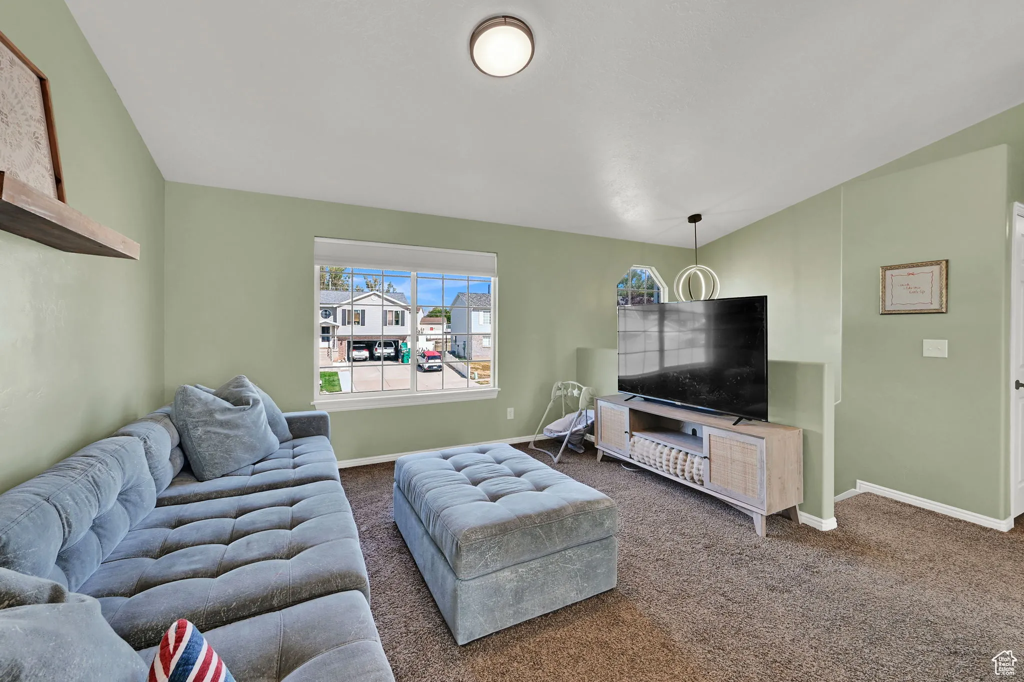 Carpeted living room featuring baseboards and lofted ceiling