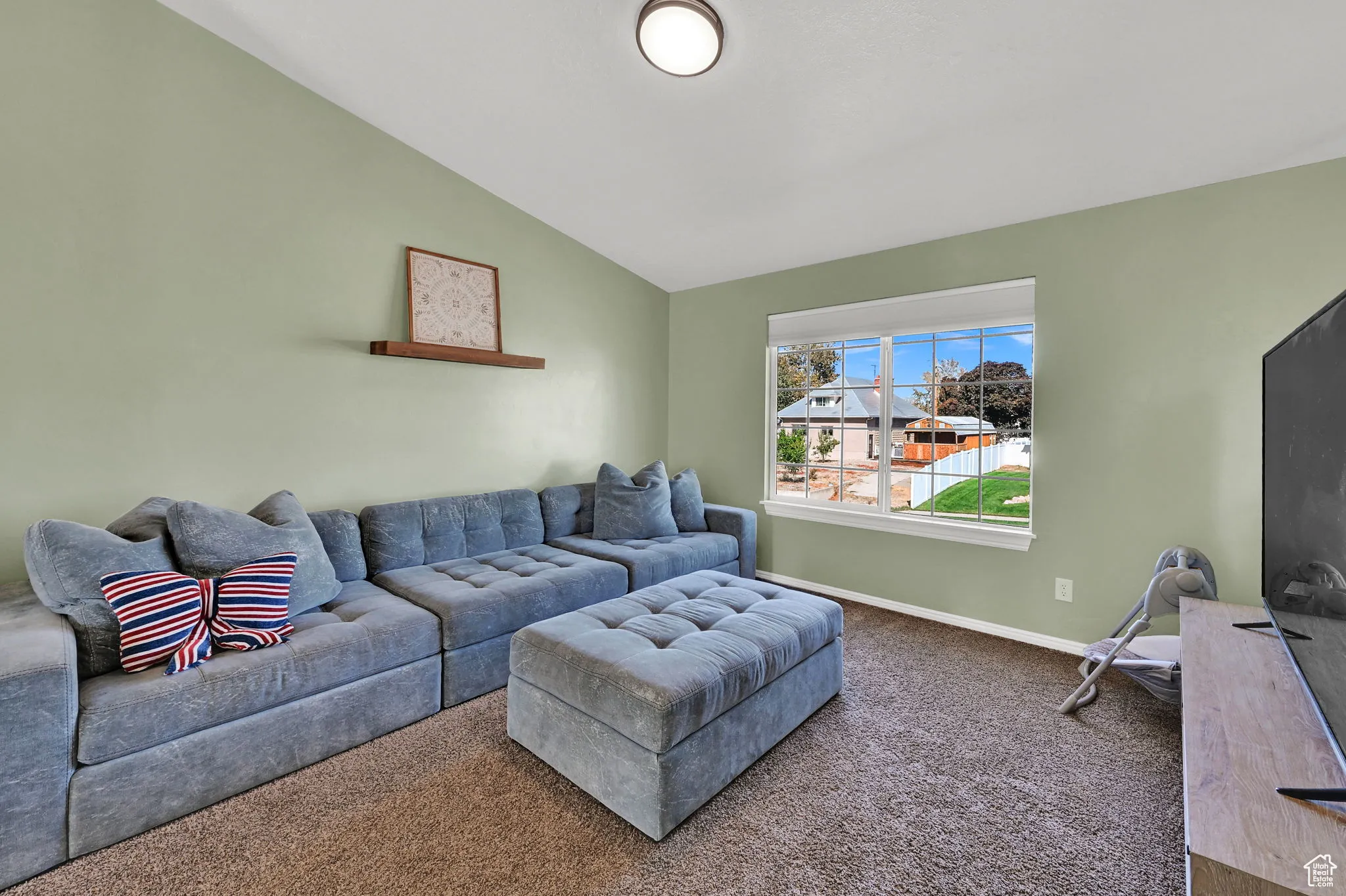 Carpeted living room featuring vaulted ceiling and baseboards