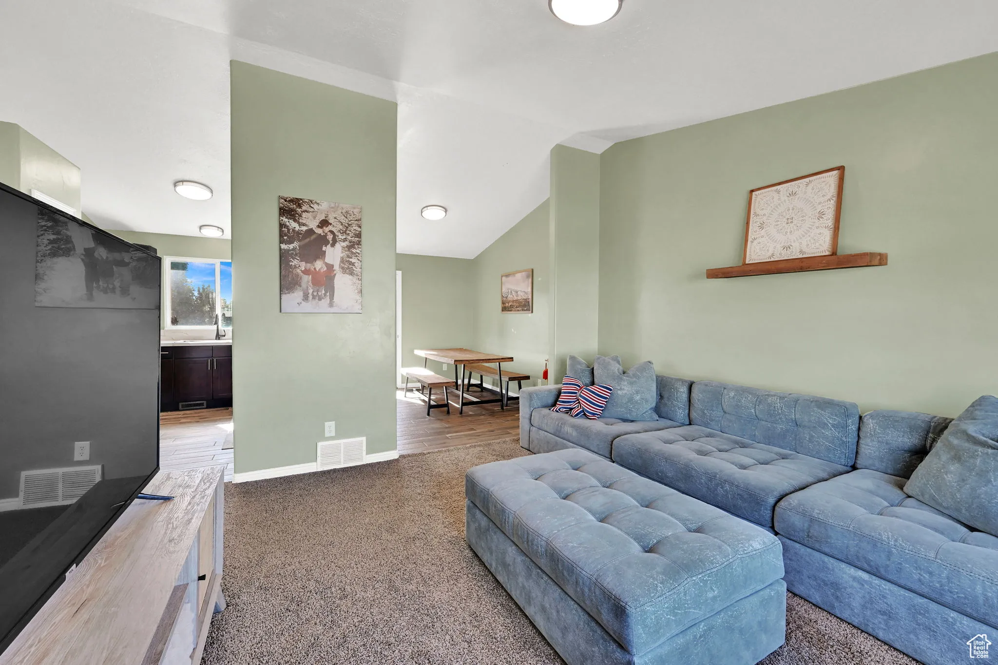 Carpeted living area featuring vaulted ceiling and baseboards