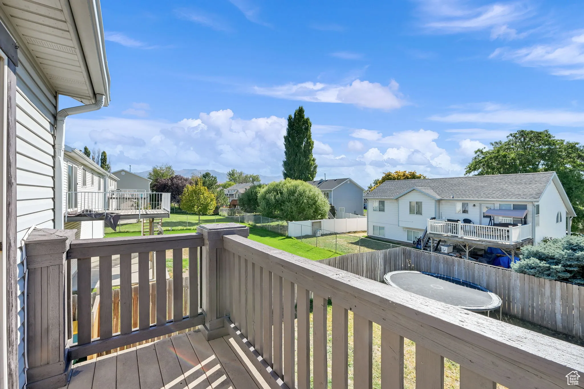 Wooden deck with a residential view, a fenced backyard, and a trampoline