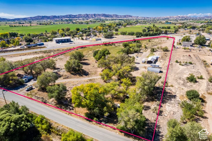 Expansive parcel featuring mature trees, a metal carport, and mountain range backdrop