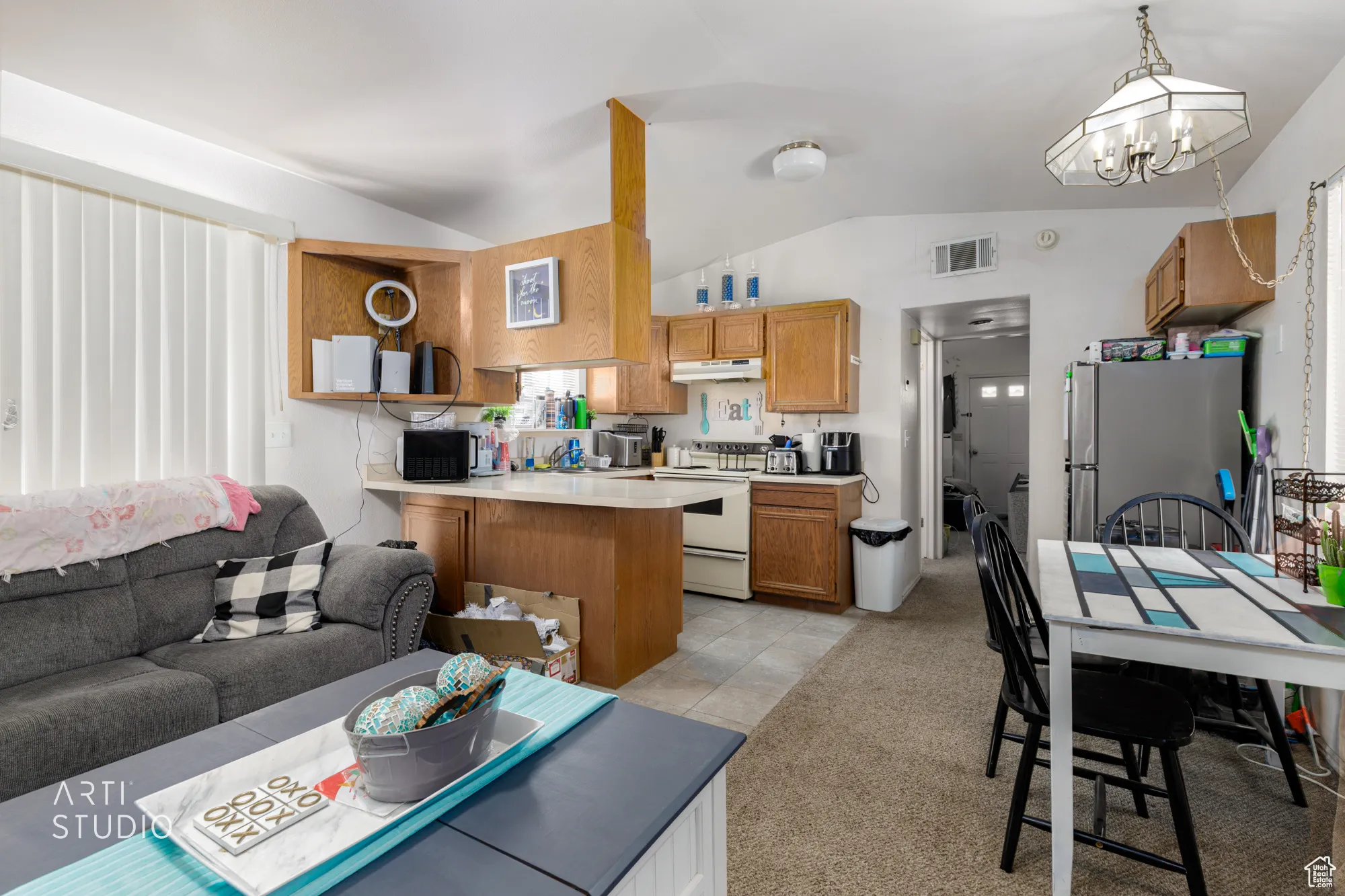 Living area featuring lofted ceiling, a chandelier, light tile patterned floors, and light colored carpet