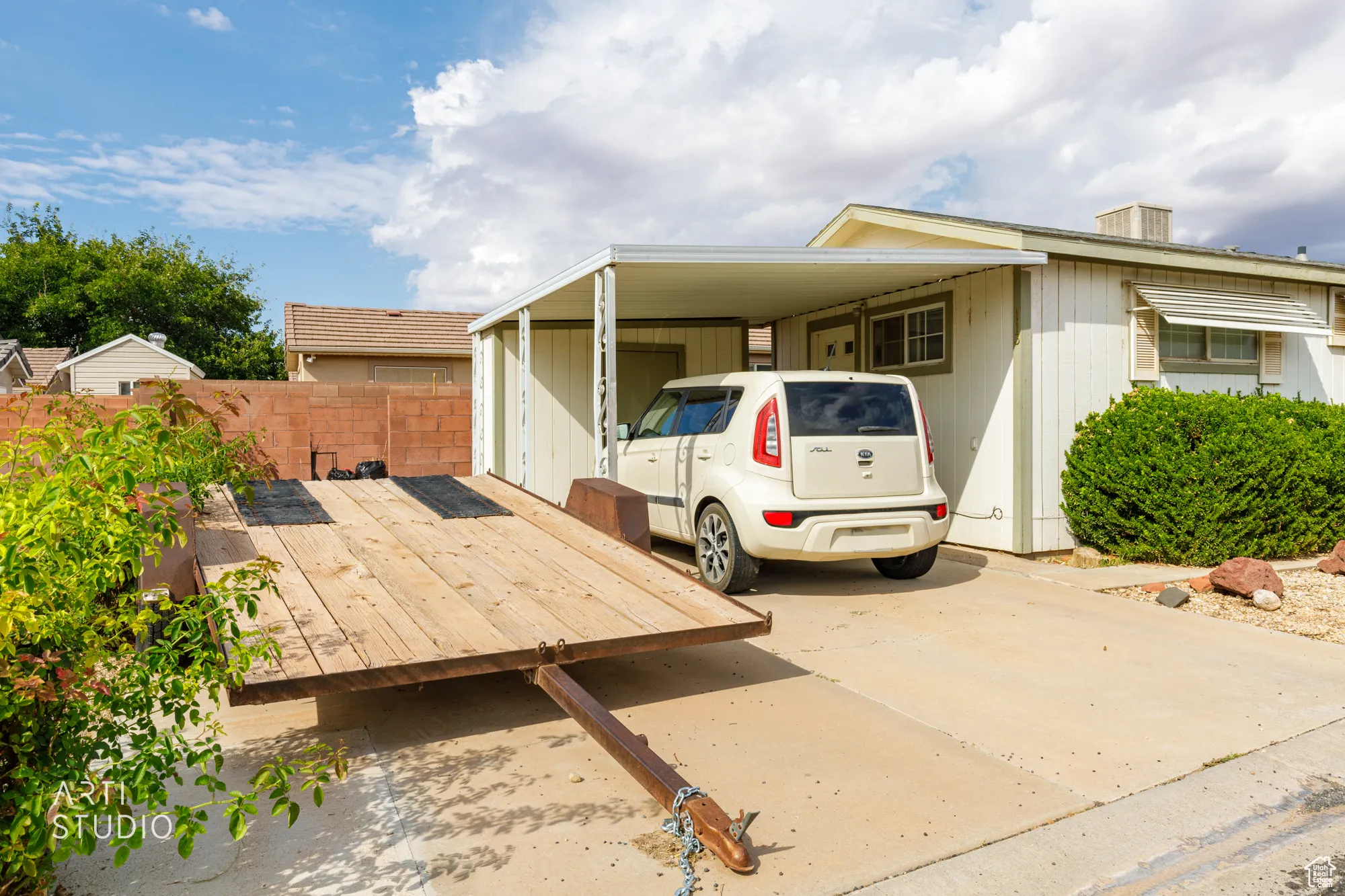 View of front facade featuring a wooden deck, an attached carport, and concrete driveway