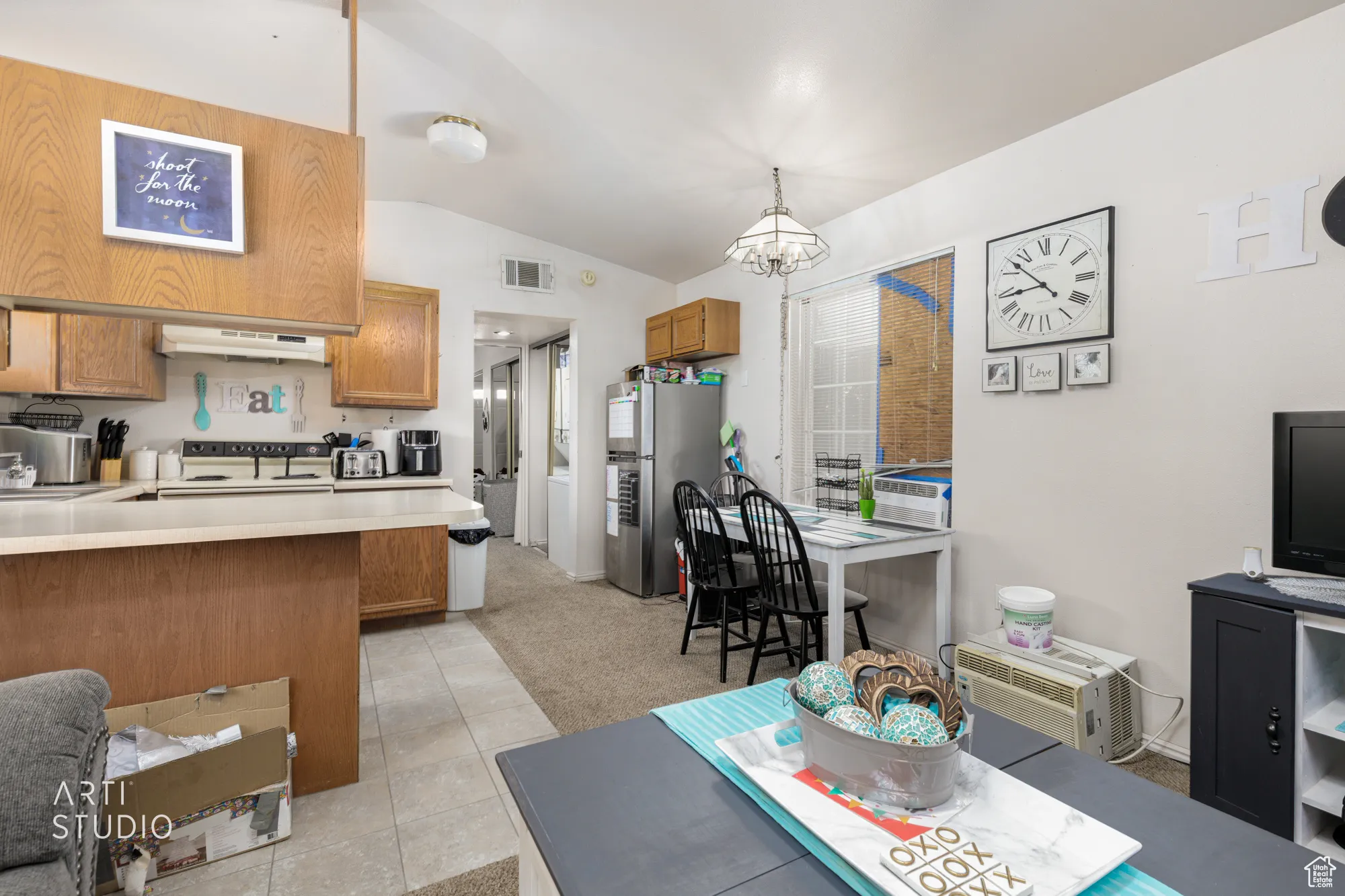 Living area with light colored carpet, vaulted ceiling, light tile patterned flooring, and a chandelier