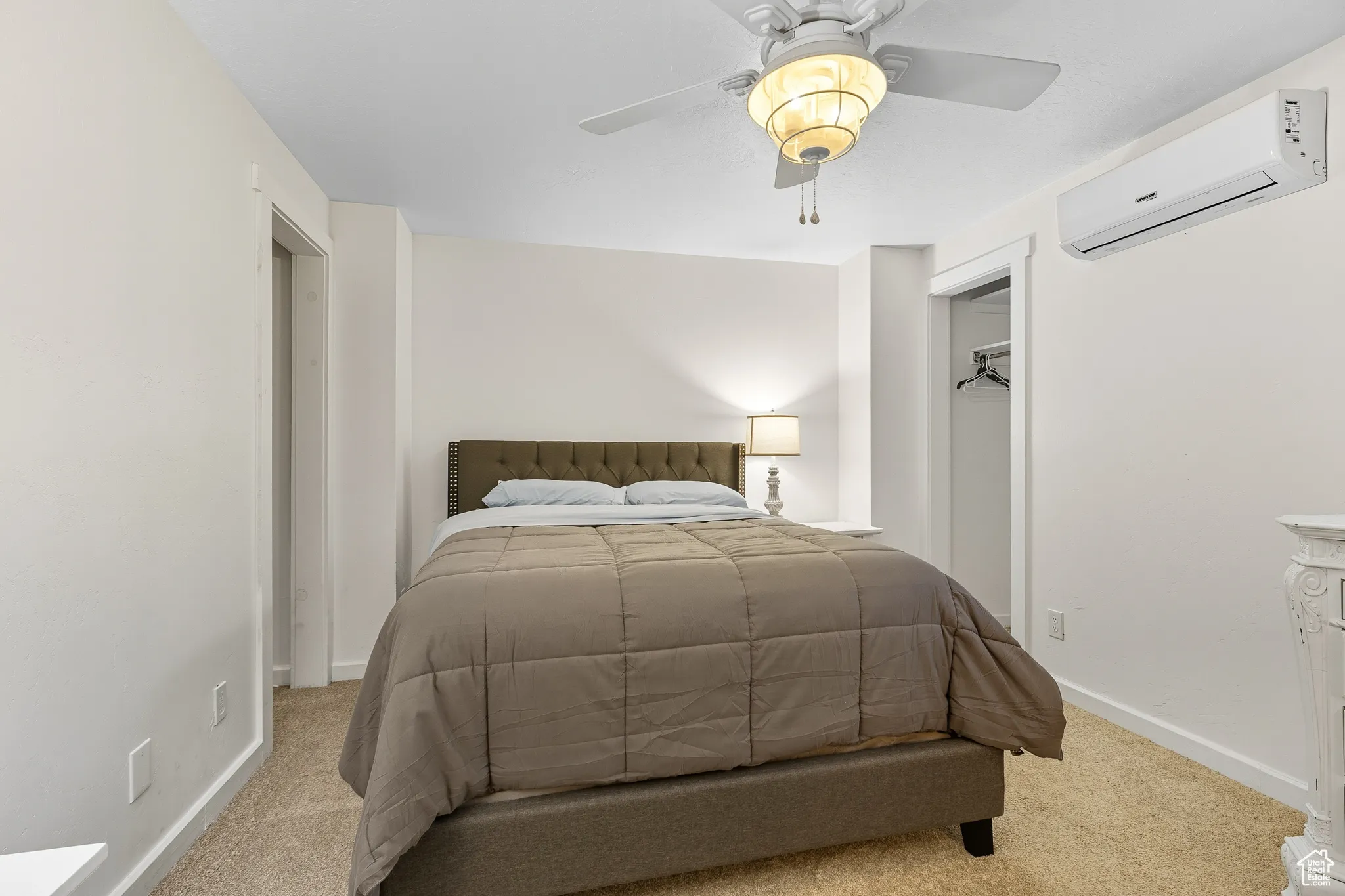 Carpeted bedroom with a wall mounted AC and a ceiling fan