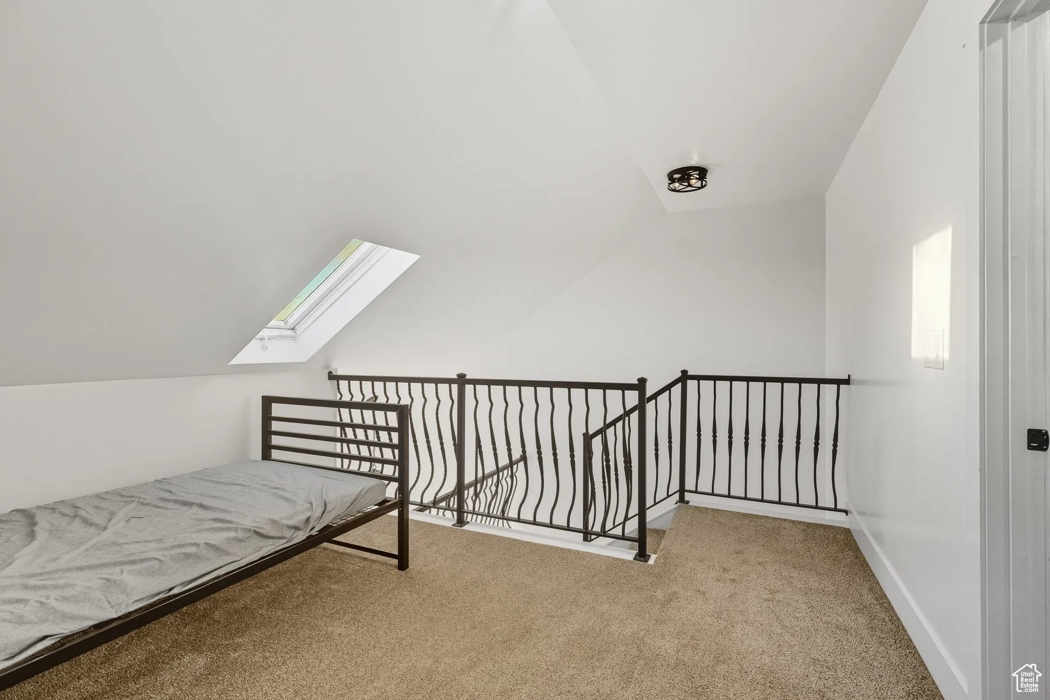 Unfurnished bedroom featuring a skylight, vaulted ceiling, and carpet flooring