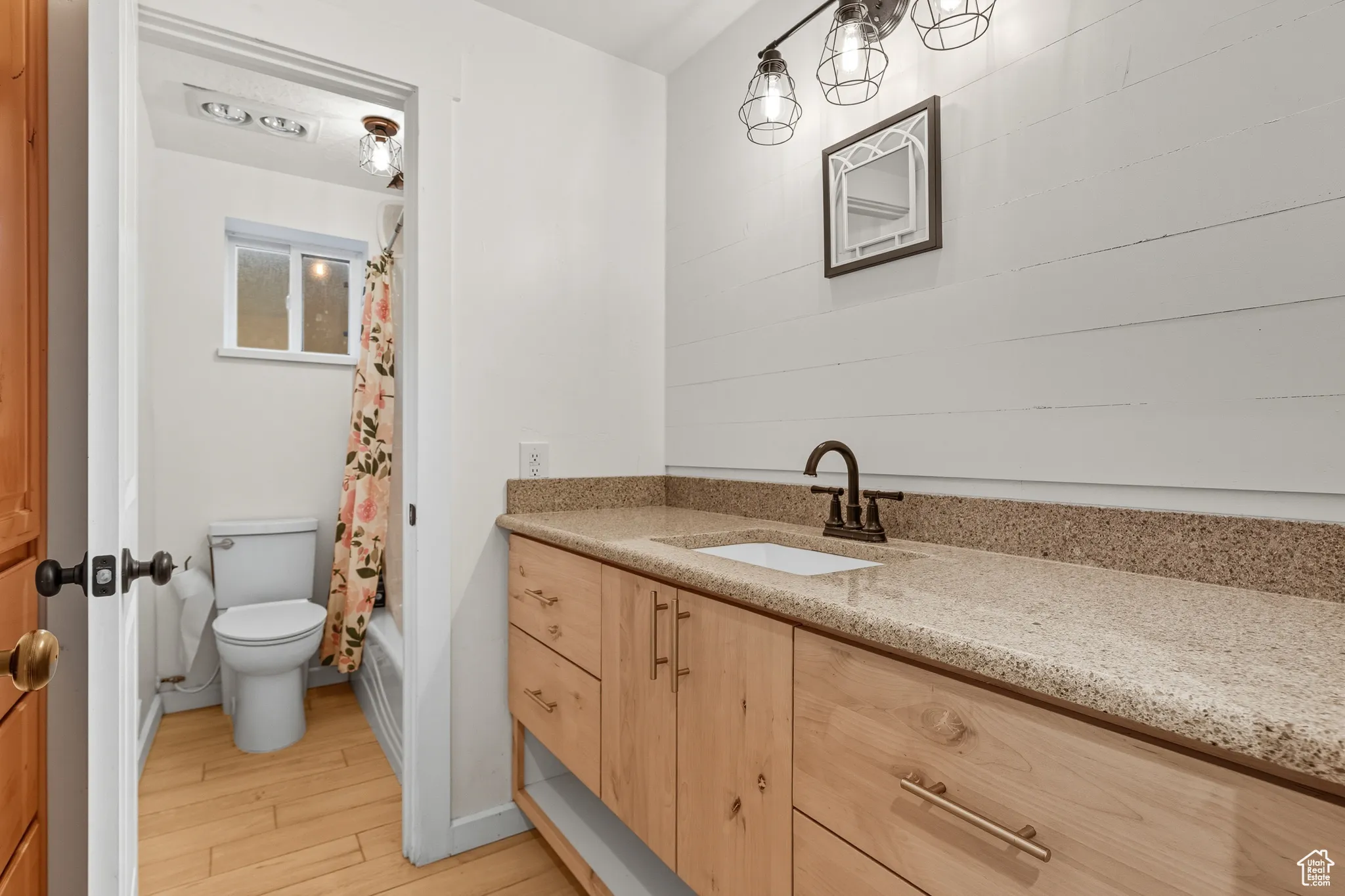 Bathroom with vanity, light wood-type flooring, and shower / bathtub combination with curtain