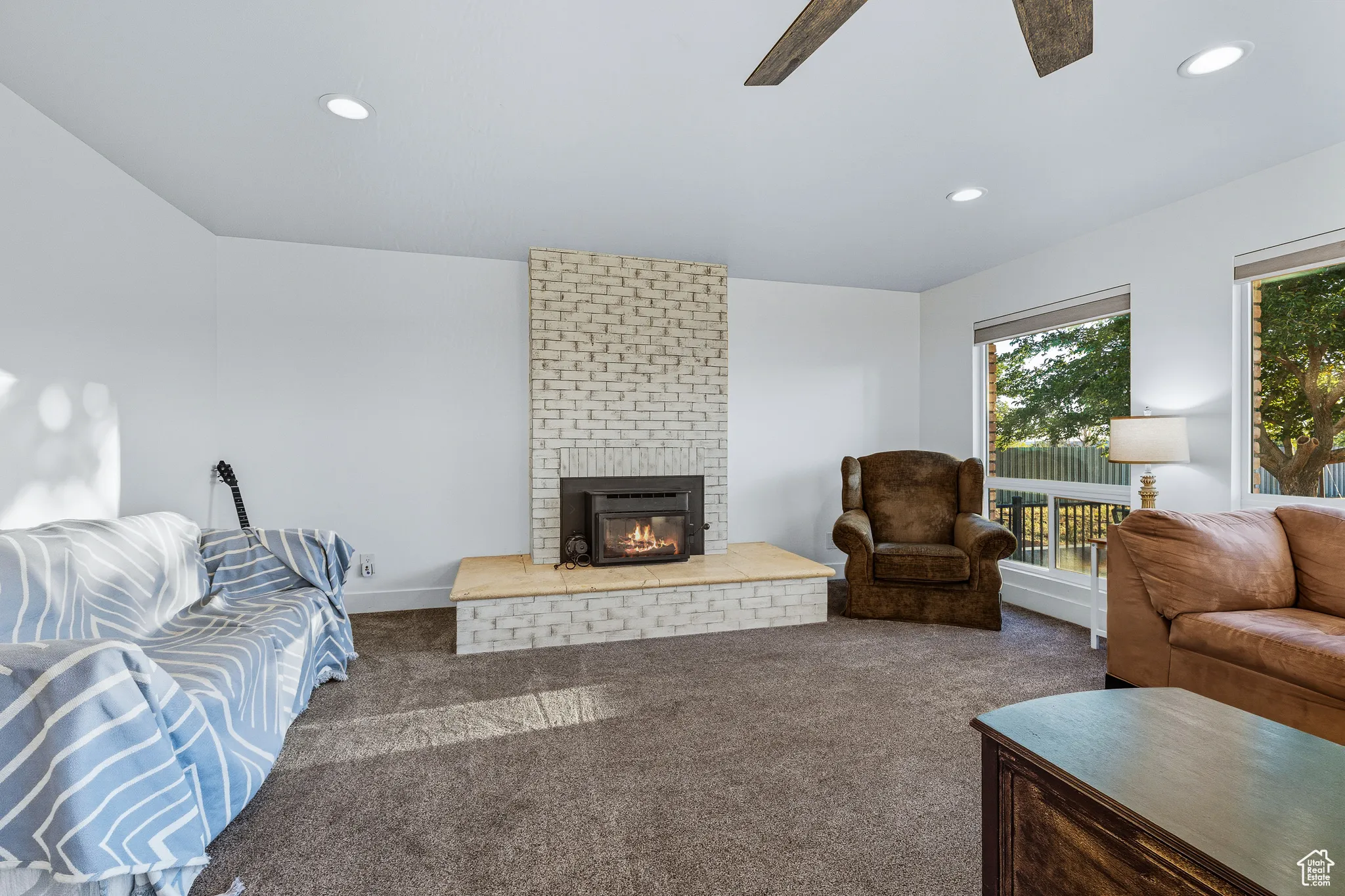 Living room with carpet, a brick fireplace, recessed lighting, and ceiling fan