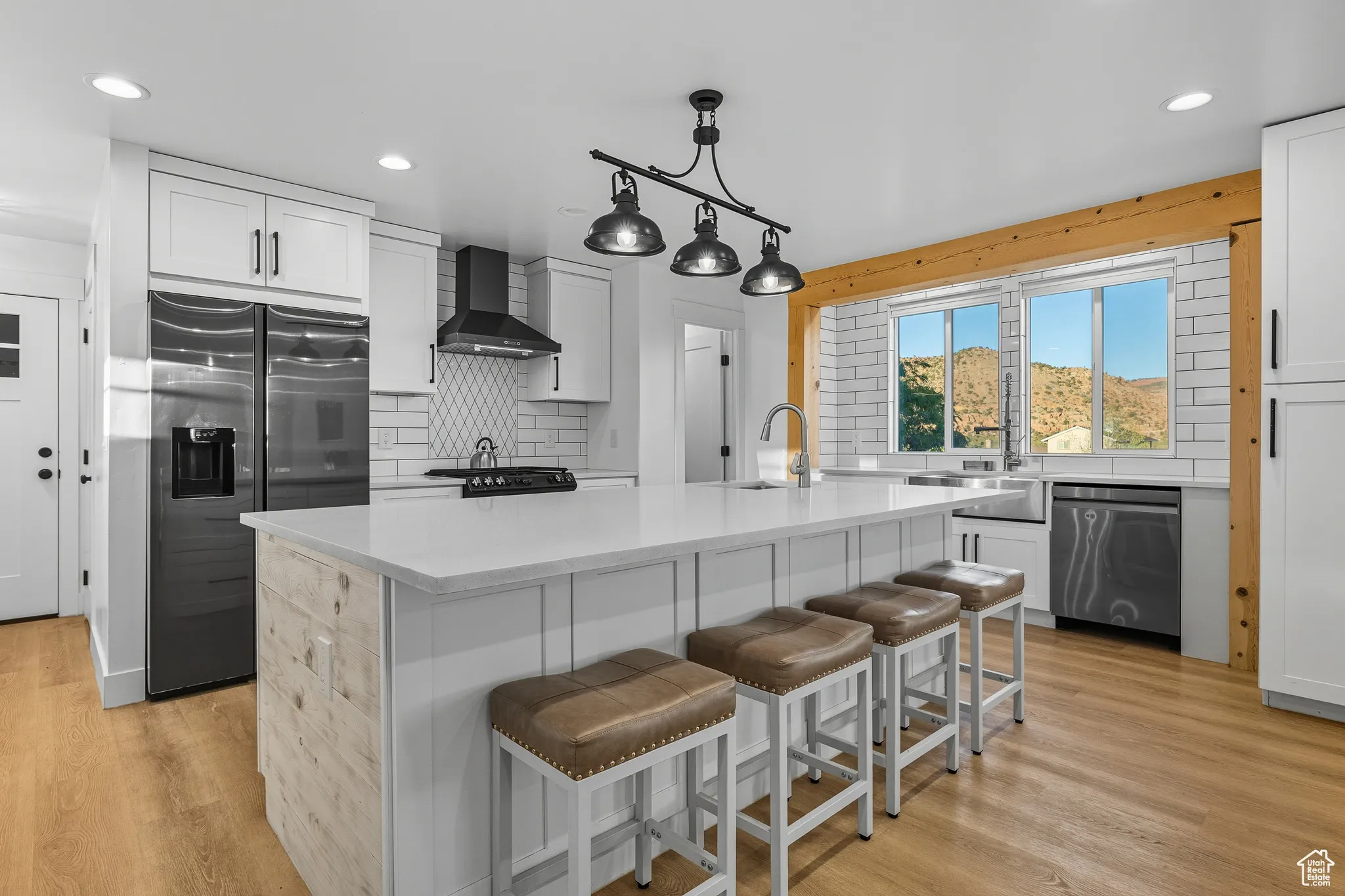 Kitchen with decorative backsplash, fridge with ice dispenser, white cabinets, light wood-style floors, and recessed lighting