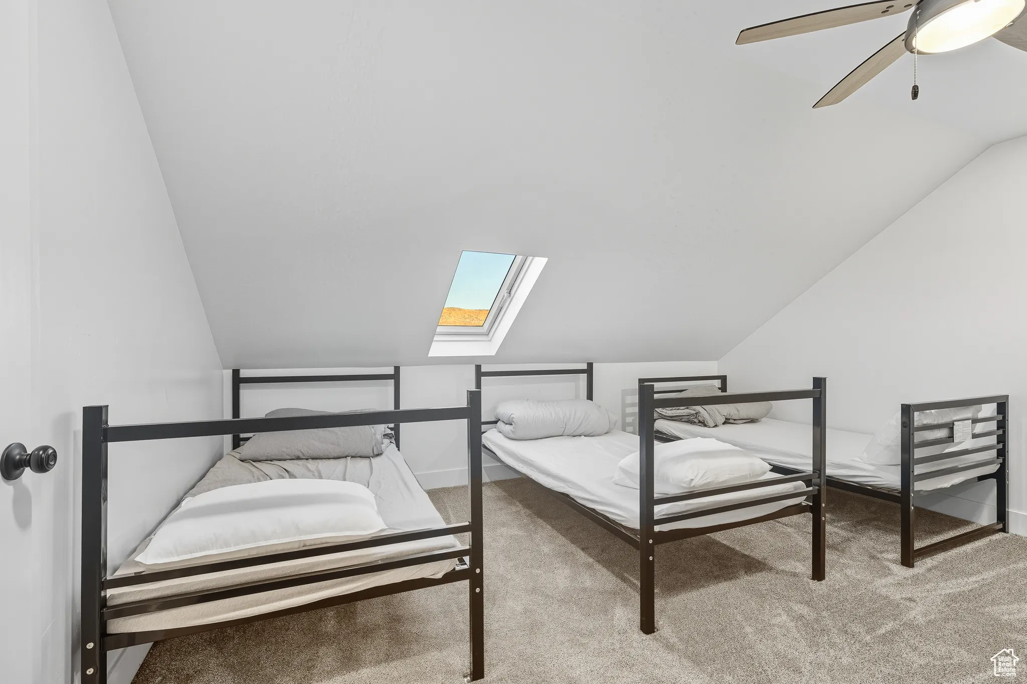 Bedroom with a skylight, light colored carpet, vaulted ceiling, and ceiling fan