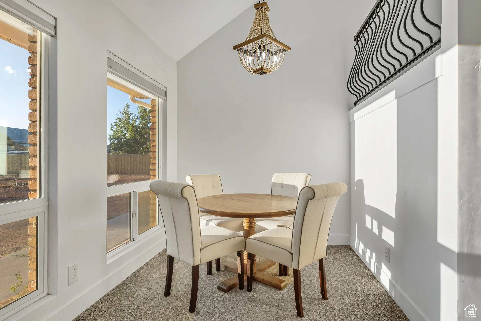 Carpeted dining room with a chandelier and high vaulted ceiling