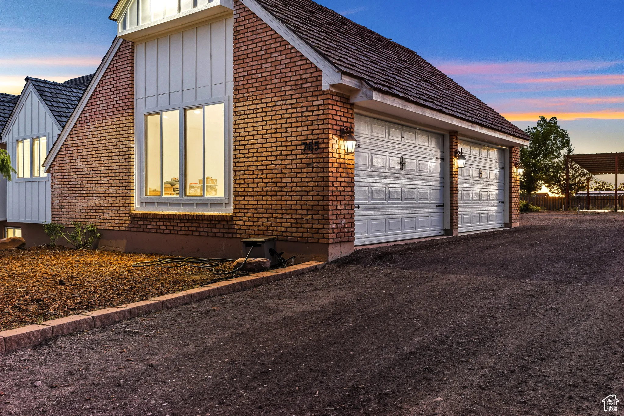 Property exterior at dusk with board and batten siding, brick siding, and a garage