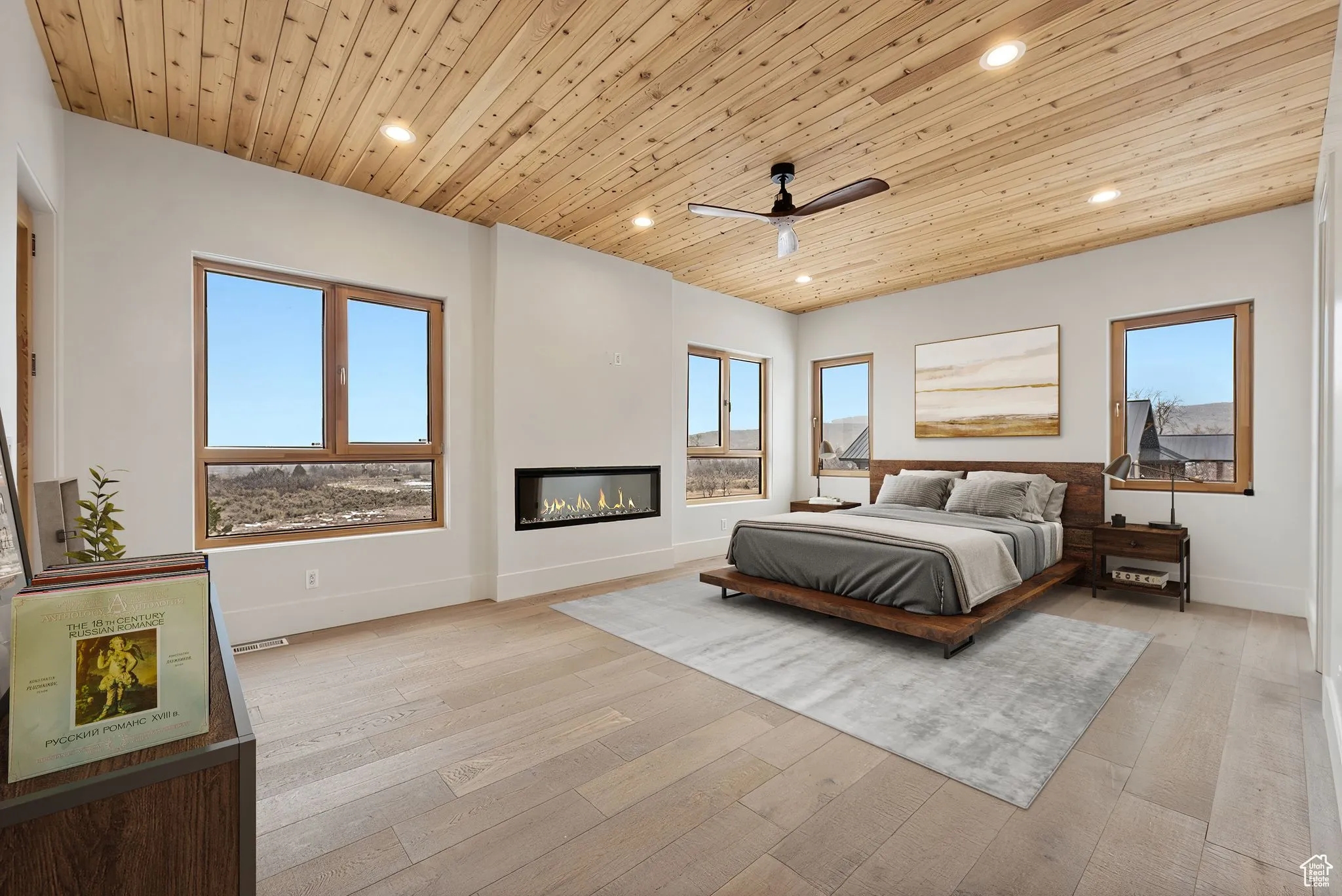 Bedroom featuring wooden ceiling, multiple windows, recessed lighting, a glass covered fireplace, and light wood-style flooring