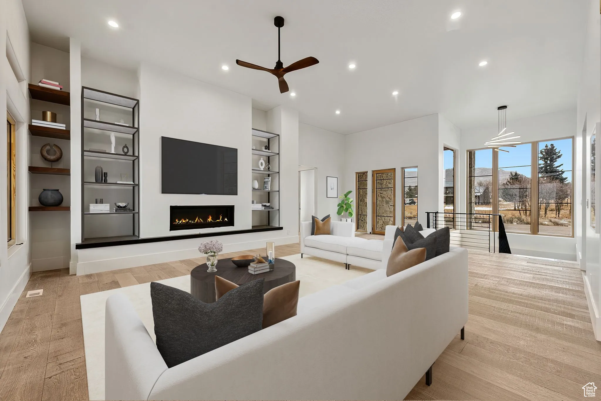 Living area featuring recessed lighting, a warm lit fireplace, built in features, light wood-style floors, and a ceiling fan