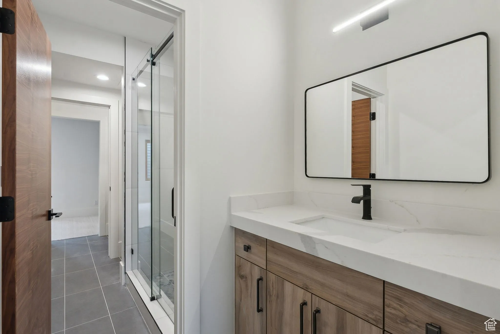 Full bathroom with vanity, light tile patterned flooring, and a shower stall
