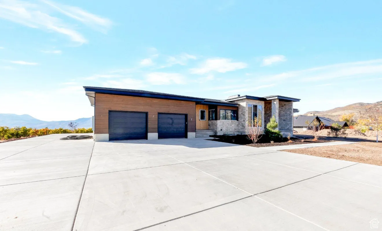 Contemporary home featuring a mountain view, stone siding, concrete driveway, and an attached garage
