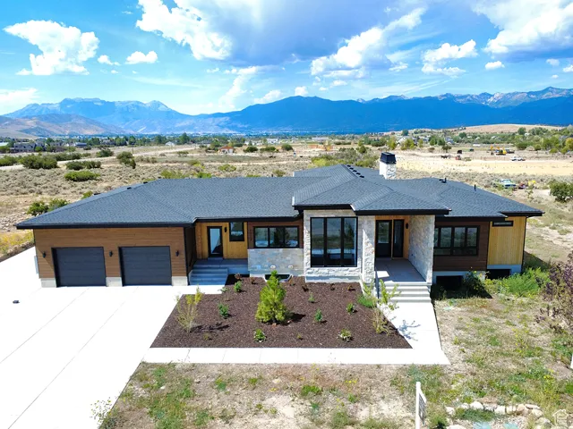 Prairie-style house featuring driveway, a mountain view, a chimney, and stone siding