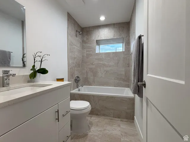 Bathroom with tiled shower / bath combo and vanity