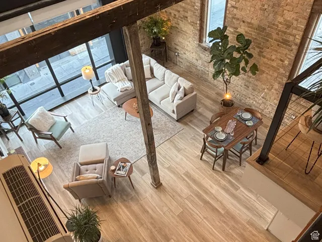 Living room featuring wood finished floors, brick wall, and a towering ceiling