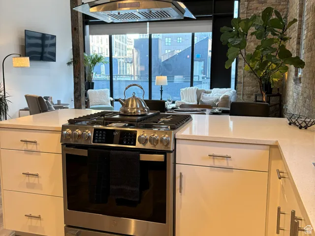 Kitchen featuring stainless steel gas range oven, island range hood, healthy amount of natural light, and light wood-style floors