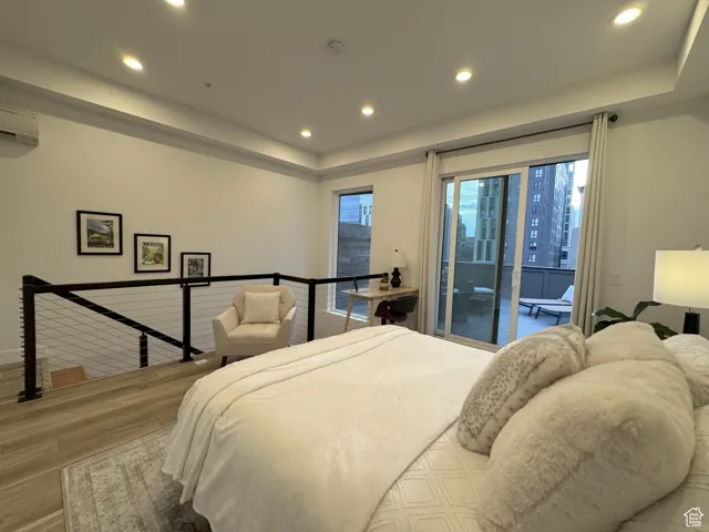 Primary Suite featuring recessed lighting, a raised ceiling, wood finished floors, access to exterior.