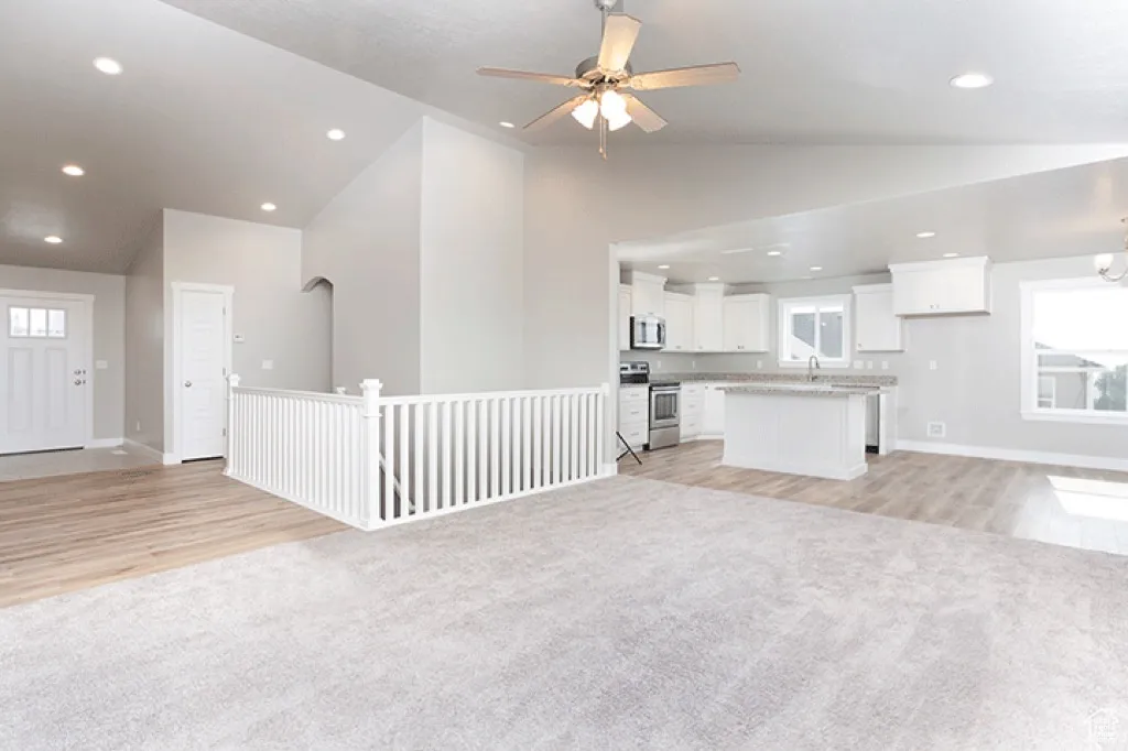 Unfurnished living room featuring light carpet, ceiling fan, recessed lighting, light wood-style flooring, and high vaulted ceiling