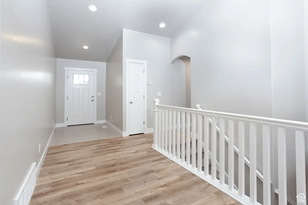 Entrance foyer with light wood-style flooring, recessed lighting, and arched walkways