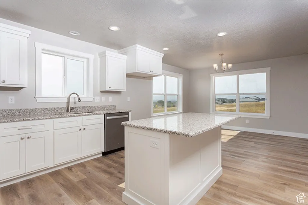 Kitchen featuring white cabinets, a textured ceiling, light stone counters, healthy amount of natural light, and recessed lighting
