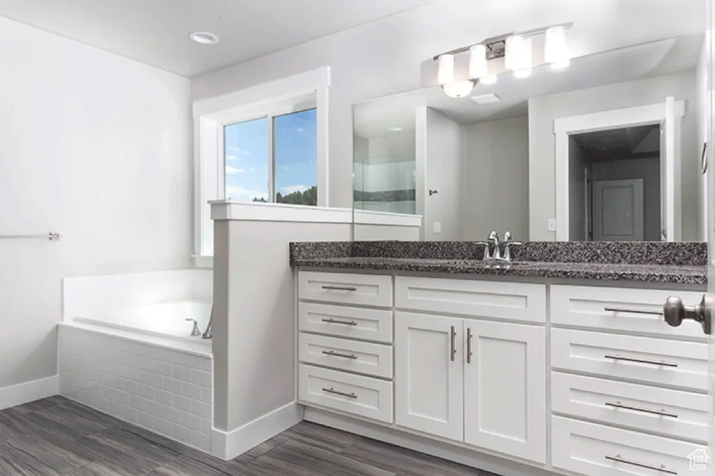 Full bath featuring vanity, a bath, and dark wood finished floors