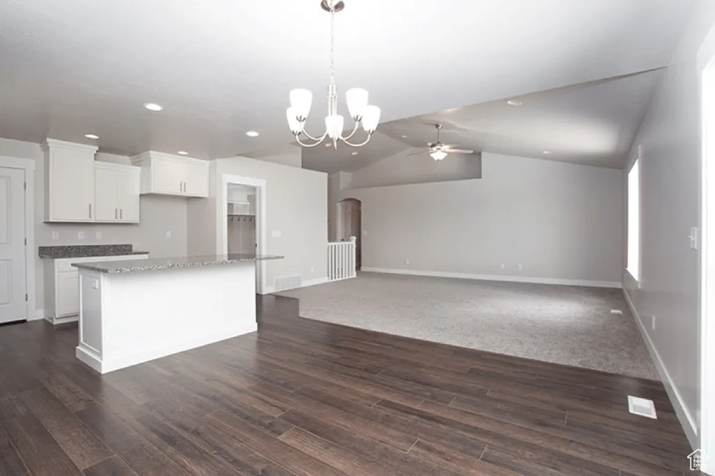 Kitchen with white cabinets, a ceiling fan, vaulted ceiling, hanging light fixtures, and a chandelier