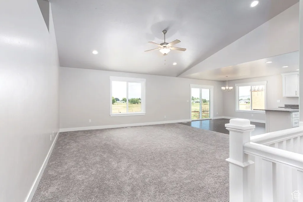 Spare room featuring carpet flooring, lofted ceiling, a ceiling fan, a chandelier, and recessed lighting