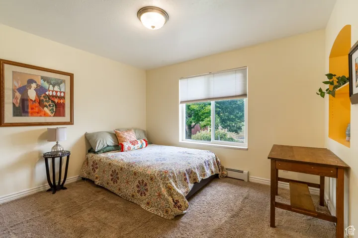 Bedroom featuring carpet and a baseboard heating unit