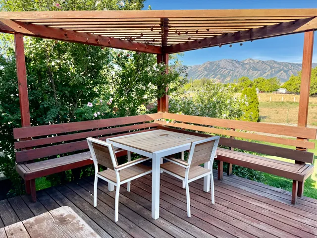 Wood-finish deck with a pergola, built-in wooden bench seating, and mountain scenery