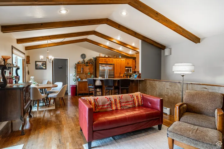 Living area with recessed lighting, a chandelier, dark wood finished floors, baseboard heating, and a wainscoted wall