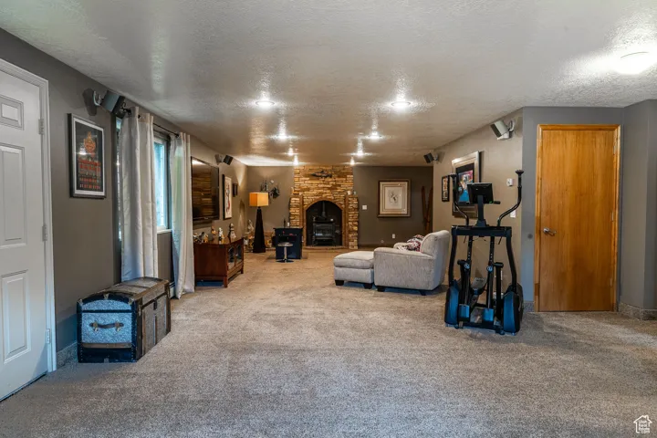 Living area with a textured ceiling, carpet floors, and a fireplace