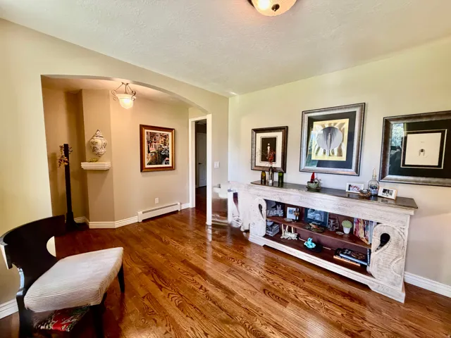 Hardwood flooring, arched doorway, recessed wall niche with built-in shelf, built-in console table with shelving, overhead flush-mount lighting