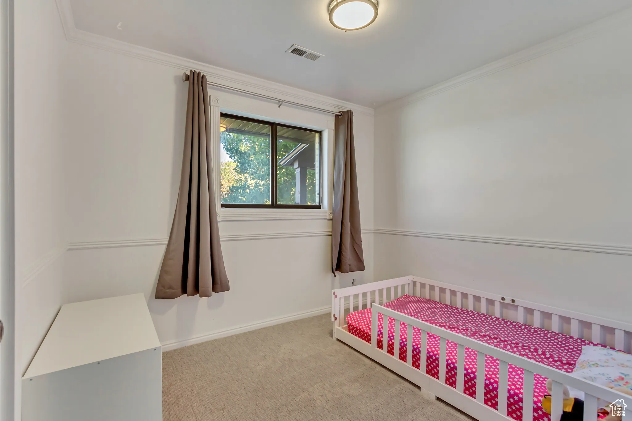 Bedroom featuring a nursery area, carpet flooring, and crown molding