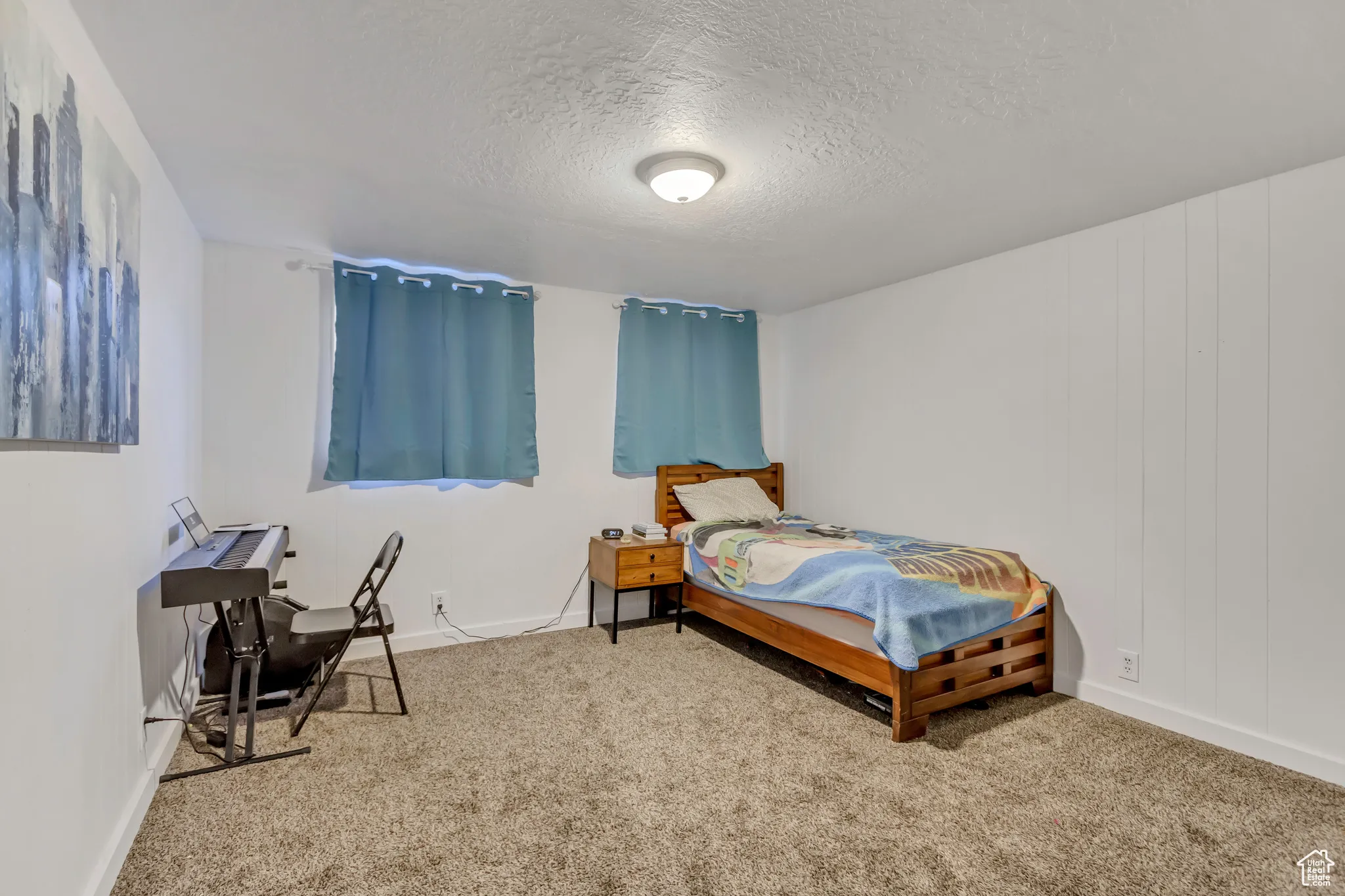 Carpeted bedroom featuring a textured ceiling and baseboards