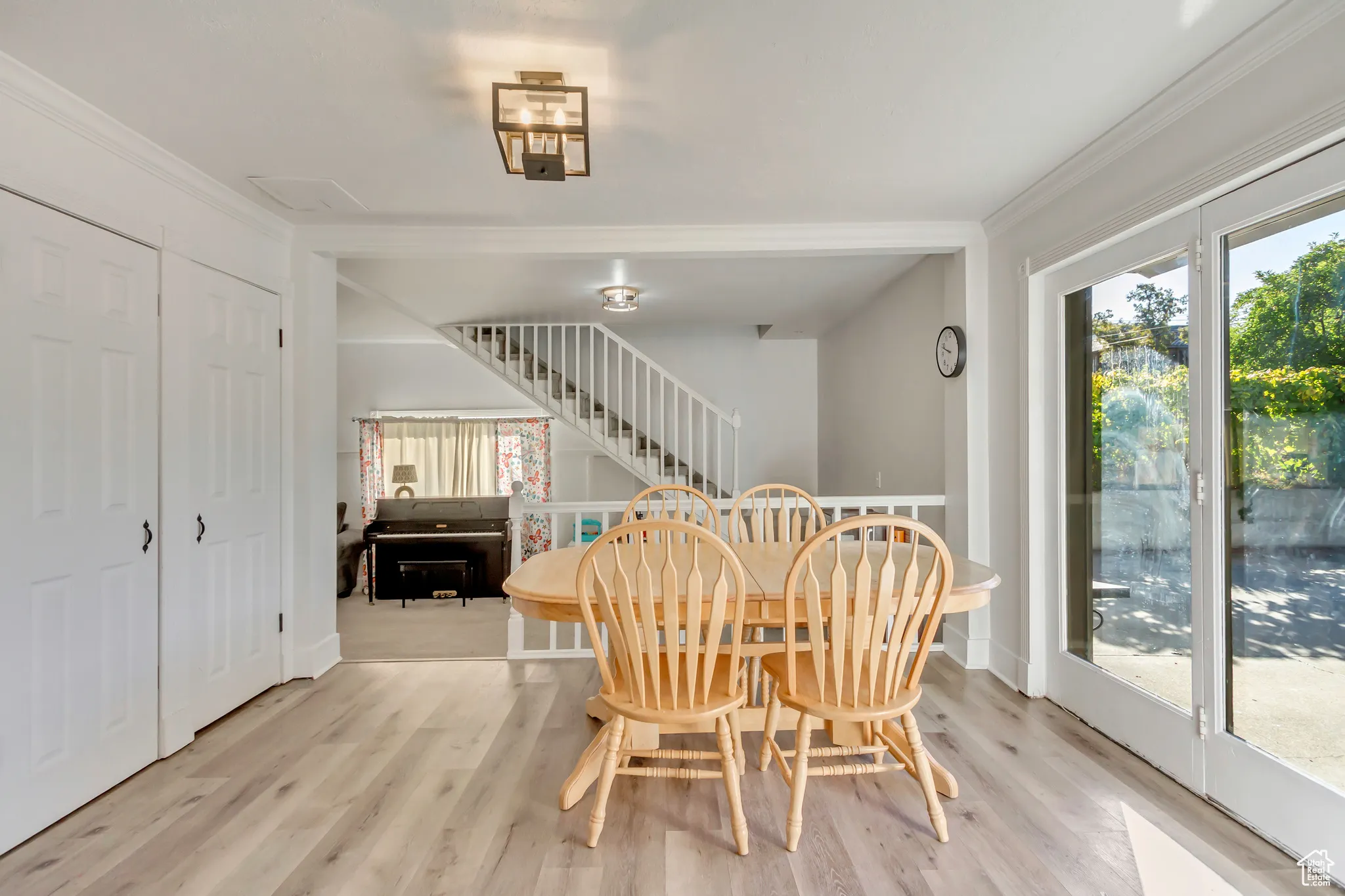 Dining space with light wood-type flooring, stairs, and ornamental molding