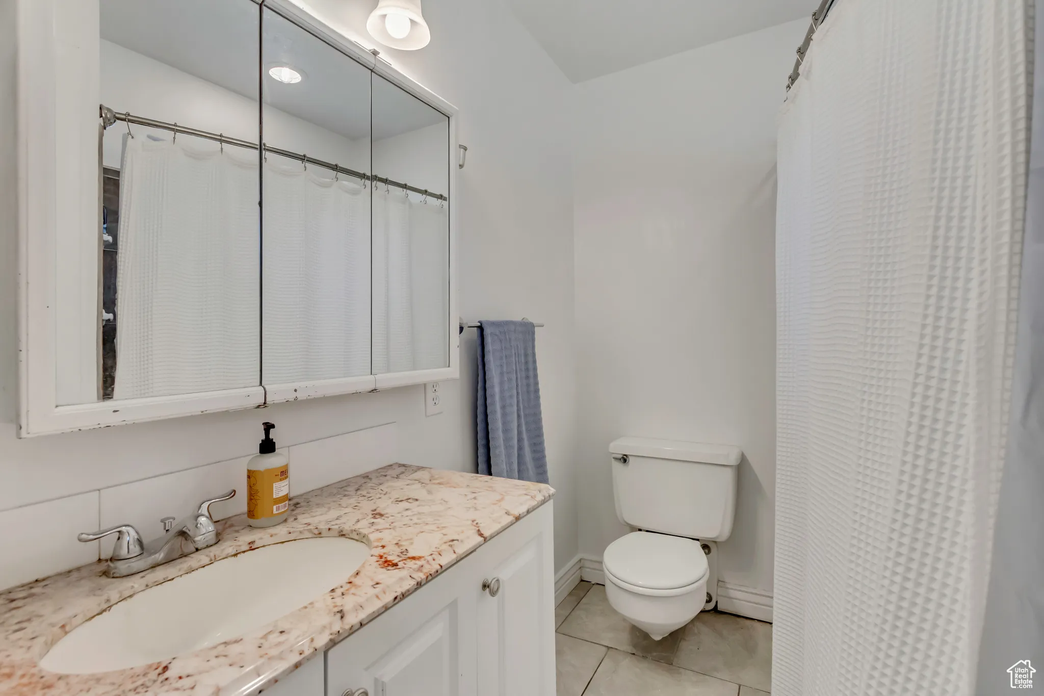 Bathroom with vanity, light tile patterned floors, and curtained shower