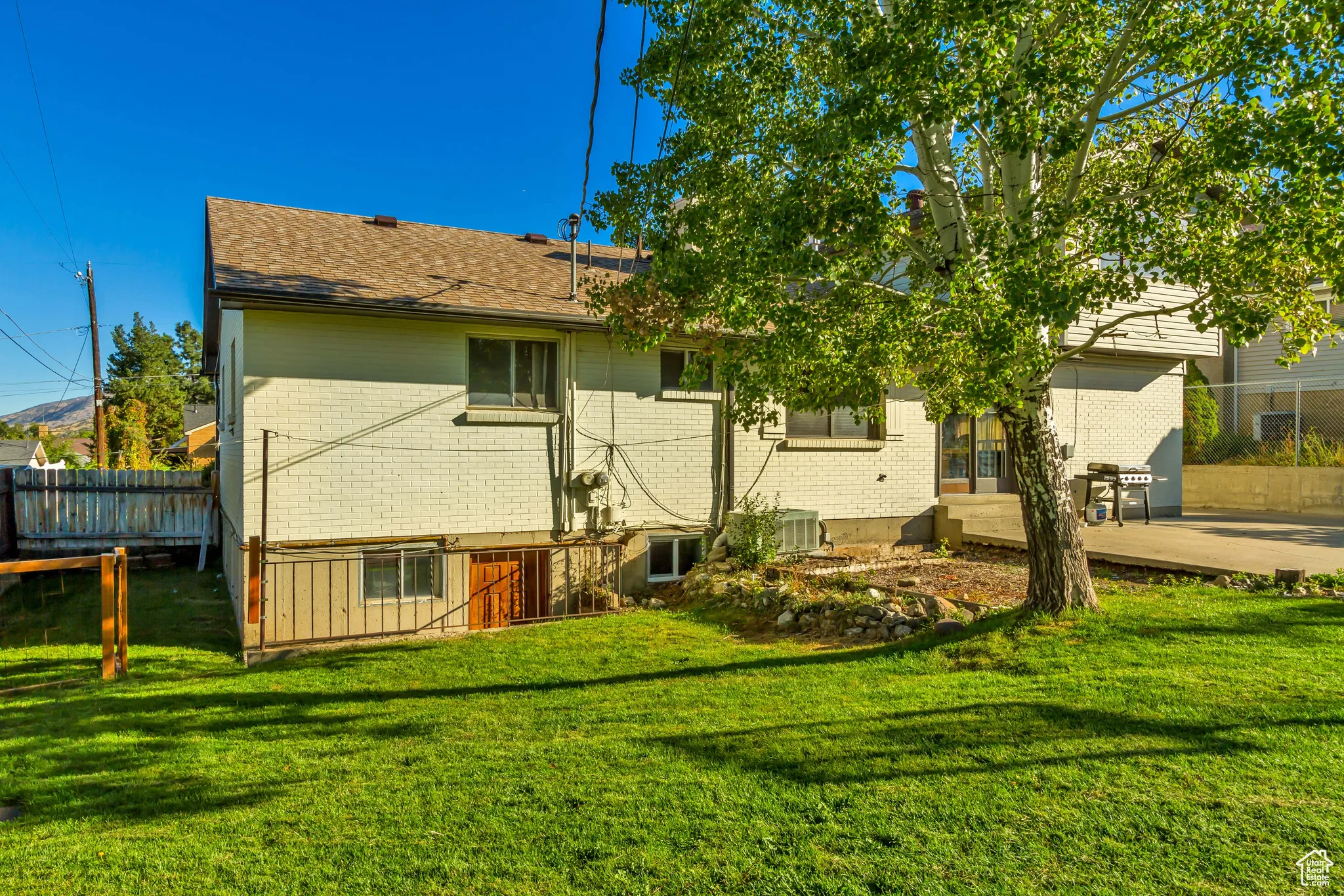 Rear view of property with brick siding, a patio, and roof with shingles