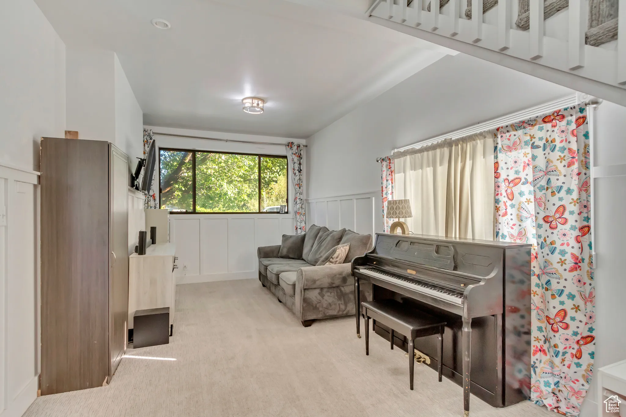 Living area with a decorative wall, a wainscoted wall, and light carpet