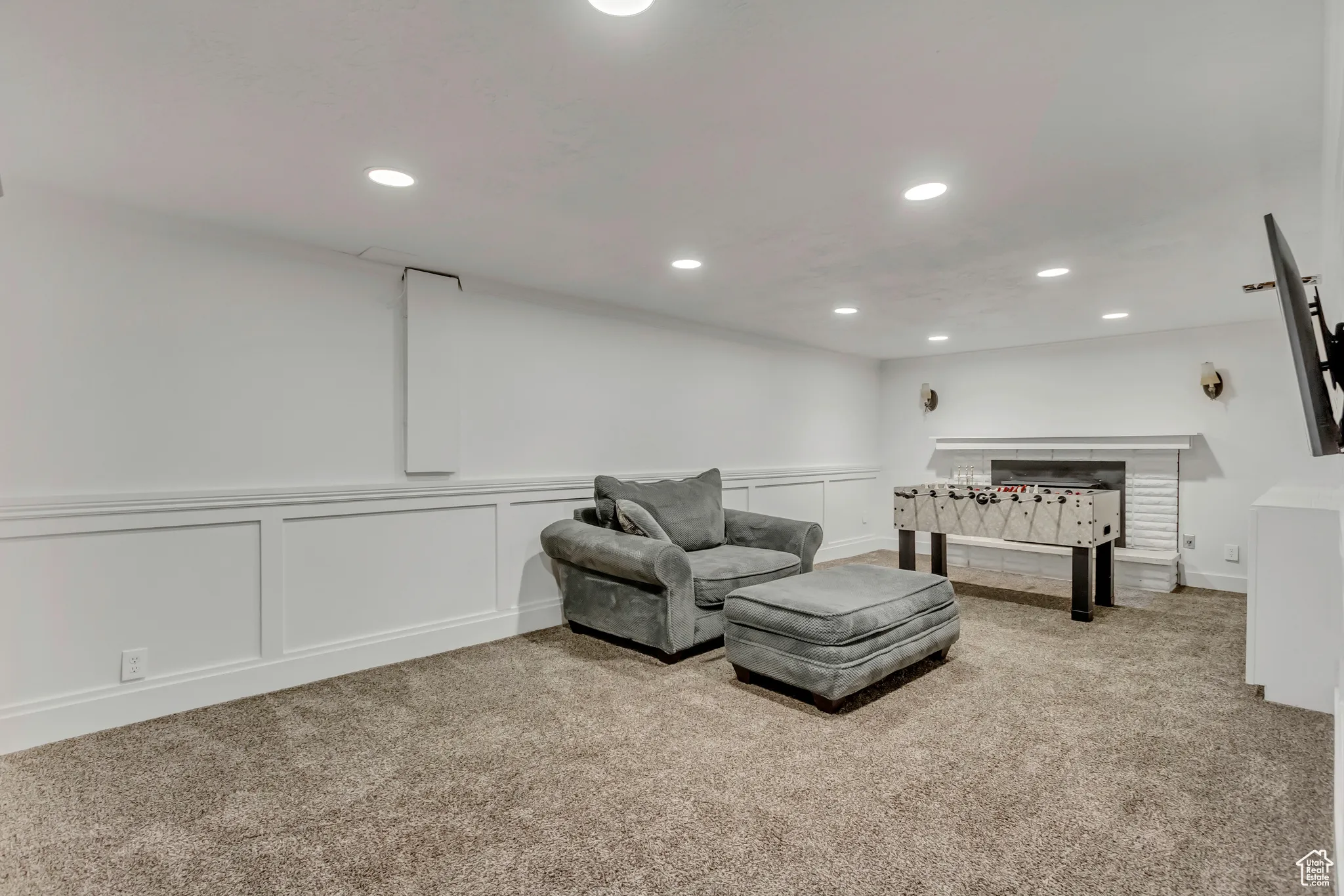Living area with a decorative wall, light colored carpet, recessed lighting, and a wainscoted wall