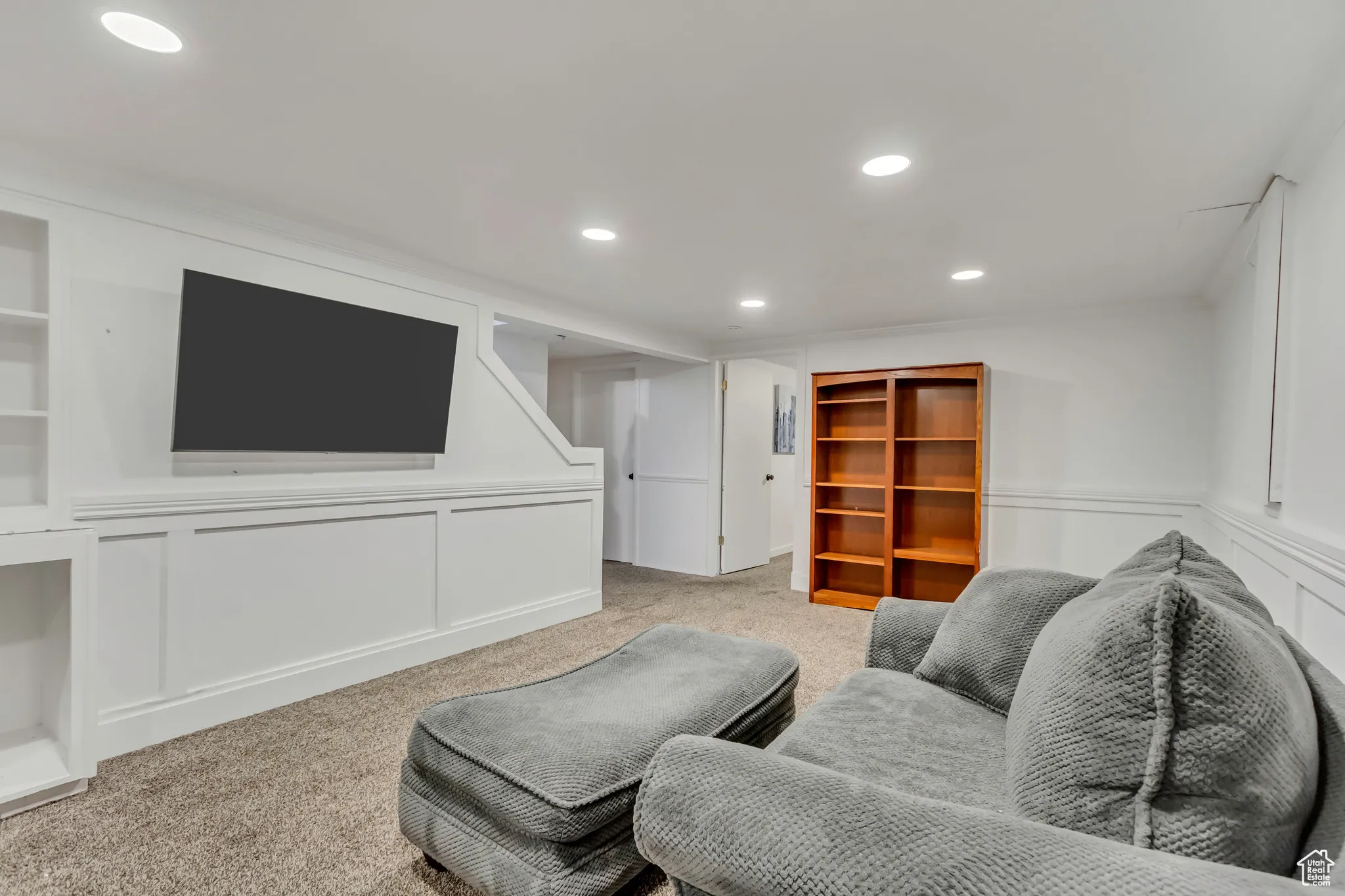 Living room featuring a decorative wall, recessed lighting, carpet floors, and wainscoting