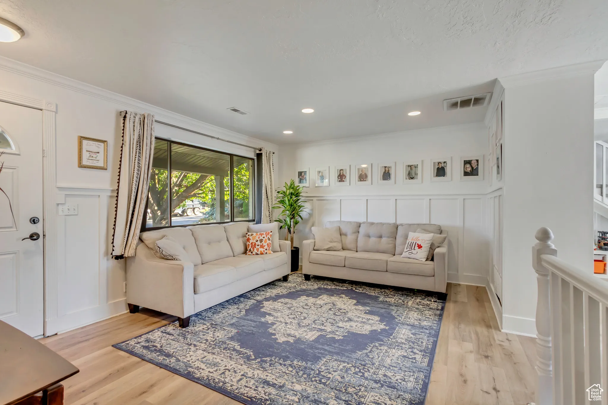 Living area featuring light wood-style flooring, ornamental molding, a decorative wall, and recessed lighting